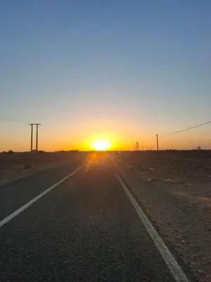 an empty road with the sunset in the desert at Sahara Luxury Room and Tours in Kasr Bounou