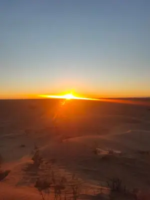a sunset in the desert with the sun setting at Sahara Luxury Room and Tours in Kasr Bounou
