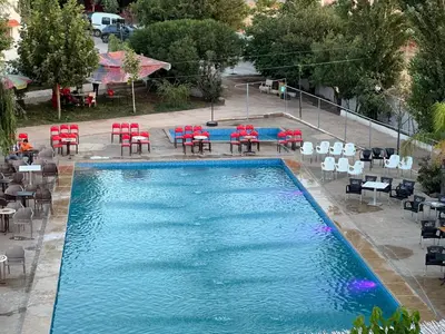 a swimming pool with red chairs and tables at Espace vert Chalet familial à Azrou in Azrou
