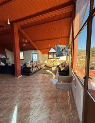 a living room filled with furniture and a large window at Espace vert Chalet familial à Azrou in Azrou