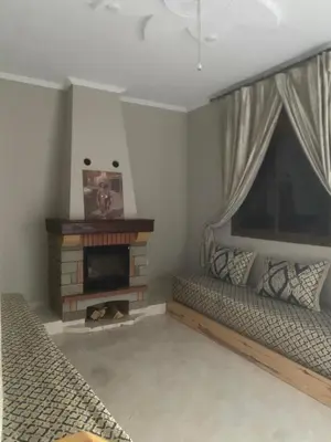 a living room with two beds and a fireplace at Espace vert Chalet familial à Azrou in Azrou