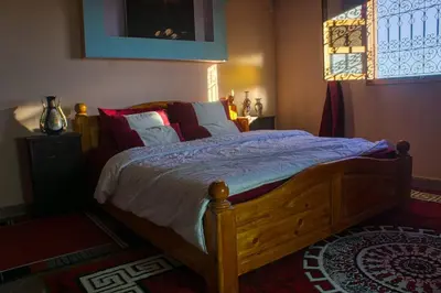 a bedroom with a wooden bed with pillows and a window at Lmtounipalace in Ouarzazate