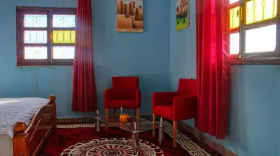 a bedroom with two red chairs and a bed at Lmtounipalace in Ouarzazate