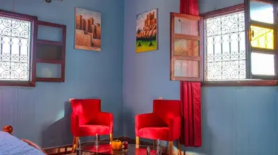two red chairs in a blue room with windows at Lmtounipalace in Ouarzazate