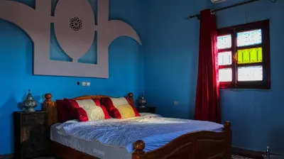 a bedroom with a bed with blue walls and a window at Lmtounipalace in Ouarzazate