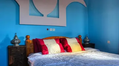 a blue bedroom with a bed with colorful pillows at Lmtounipalace in Ouarzazate