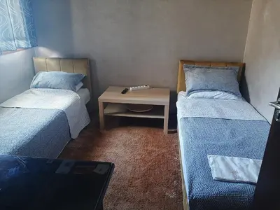 a small room with two beds and a table at Chambre d'hôte jardins de Hamria in Meknès