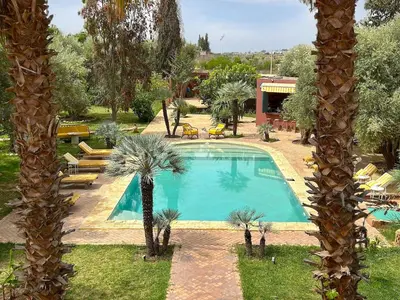 a swimming pool in a yard with palm trees at Palais Julia in Chouiter