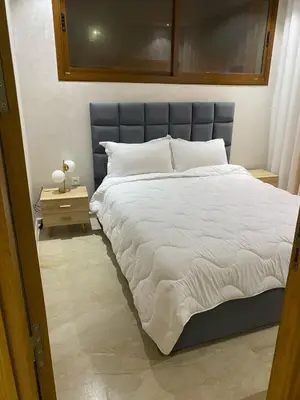 a bedroom with a large white bed with a blue headboard at Apartment Ocean view in Oulad Akkou