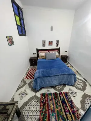 a bedroom with a bed with a blue blanket and a rug at Dar Bladi -A Quiet Place to Reset in Fes in Fès