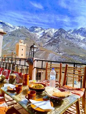 a table with food on top of a balcony with mountains at Gite Likemte Tachdirt in Tacheddirt