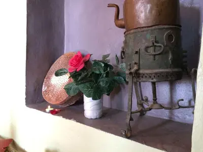a red rose in a vase next to a stove at Gite Likemte Tachdirt in Tacheddirt