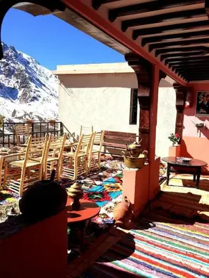 a patio with chairs and tables and a mountain at Gite Likemte Tachdirt in Tacheddirt