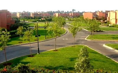 an empty street with trees and a road in a city at Appartement á Loisis á Bensimane in Oulad Akkou