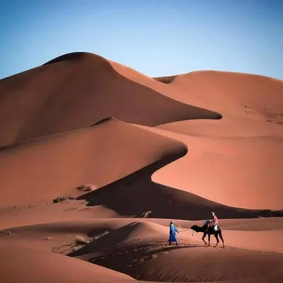 two people riding a camel in the desert at Nada luxury desert camp in Merzouga
