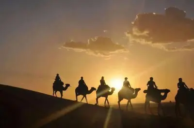 a group of people riding horses in the desert at sunset at Nada luxury desert camp in Merzouga