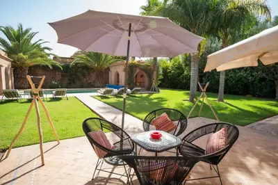 a table with chairs and an umbrella on a patio at Villa luxe ADAMA avec gouvernante- Marrakech in Marrakech