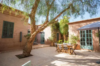 a patio with a table and chairs under a tree at Villa luxe ADAMA avec gouvernante- Marrakech in Marrakech