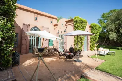 a patio with chairs and umbrellas in front of a house at Villa luxe ADAMA avec gouvernante- Marrakech in Marrakech