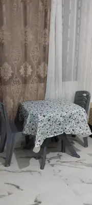 a table and chairs in a room with a curtain at Petit appartement in Meknès