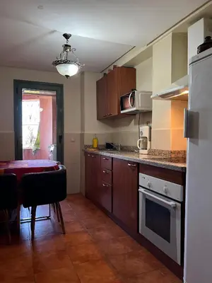 a kitchen with wooden cabinets and a table in it at Duplex de rêve en face du jardin majorelle in Oulad Akkou