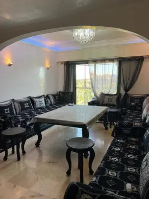 a living room with a table and a couch at Duplex de rêve en face du jardin majorelle in Oulad Akkou
