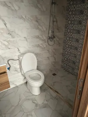 a white bathroom with a toilet and a shower at Les jardins de temara in Oulad Akkou