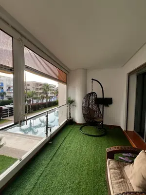 a living room with a green carpet and a large window at Dyar lbahr in Oulad Akkou