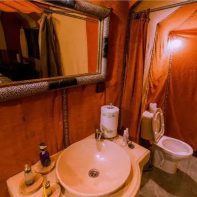 a bathroom with a sink and a toilet and a mirror at Yamanda luxury camp in Merzouga