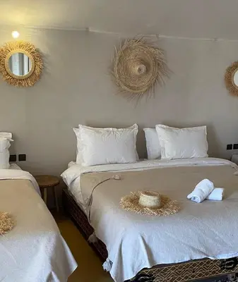 a bedroom with two beds with white sheets and two mirrors at Yamanda luxury camp in Merzouga