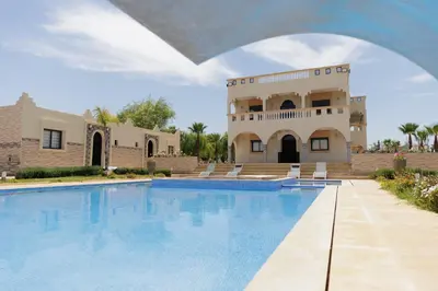 a house with a swimming pool in front of a building at Villa La Rêverie in Ain Cheggag