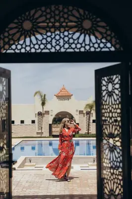 a woman in a red dress standing in front of a pool at Villa La Rêverie in Ain Cheggag