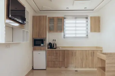 a kitchen with wooden cabinets and a white refrigerator at Villa La Rêverie in Ain Cheggag
