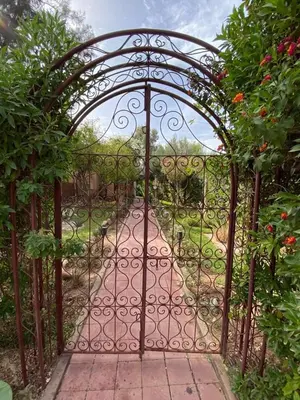 an iron gate leading to a garden with a dirt road at Beautiful Moroccan-style villa in Douar Soukkane