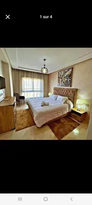 a bedroom with a large bed and a desk at Appart bien meublé pour location in Oulad Akkou