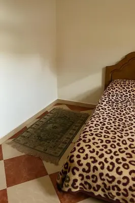 a corner of a room with a bed and a rug at Résidence Kawtar Meknès in Meknès
