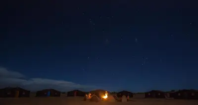 a group of tents in the desert at night at Sahara Desert Camp Mhamid - Bivouac Le Pacha in Mhamid