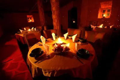 a table in a restaurant with candles on it at Sahara Desert Camp Mhamid - Bivouac Le Pacha in Mhamid