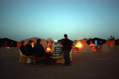 a group of people sitting in chairs in a desert at Sahara Desert Camp Mhamid - Bivouac Le Pacha in Mhamid