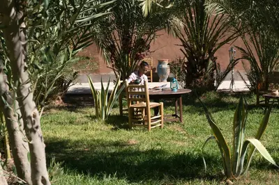 a woman sitting at a table in a garden at Casa Juan in Tagounite
