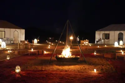 a fire pit with lights in a field at night at Merzouga LUXURY TENT in Merzouga