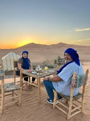 two people sitting at a table in the desert at Merzouga LUXURY TENT in Merzouga