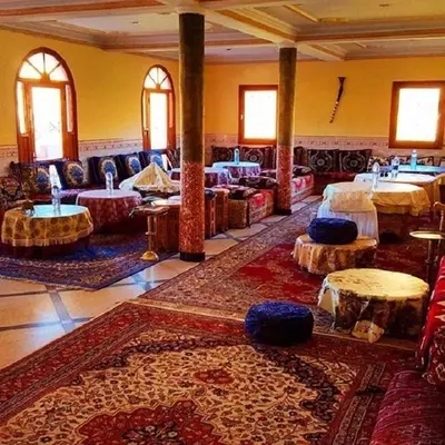 a large room with tables and couches and rugs at Hotel Boutaghrar in Kalaat MGouna