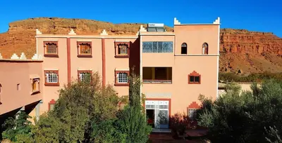 a building with a mountain in the background at Hotel Boutaghrar in Kalaat MGouna