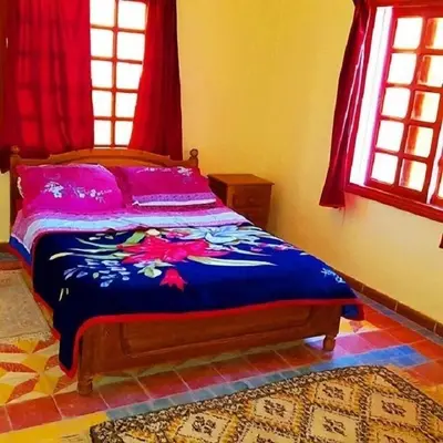 a bedroom with a bed with a blue comforter at Hotel Boutaghrar in Kalaat MGouna