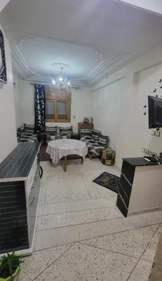 a living room with a table and a tv at Apartment low price good location in Fès