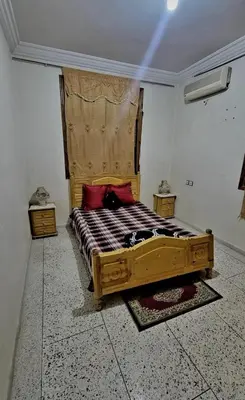 a bedroom with a wooden bed with red pillows at Apartment low price good location in Fès