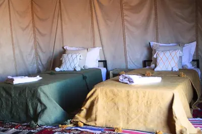 a room with two beds with blankets and pillows at Bivouac Le secret des dunes, lac Iriqui in Foum Zguid
