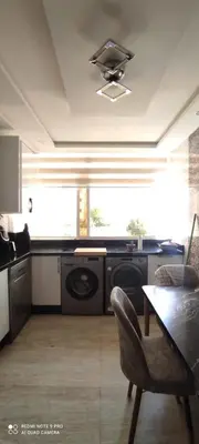 a kitchen with a washing machine and a table with a chair at Sublime appartement front de mer in Oulad Akkou