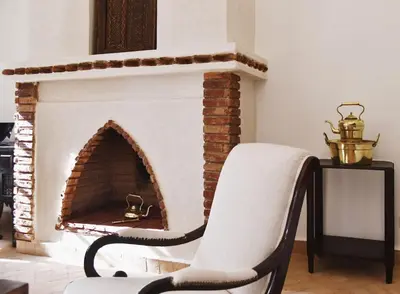 a living room with a chair and a fireplace at Riad Arraha Retreat Elegance tranquility and pools in Marrakech